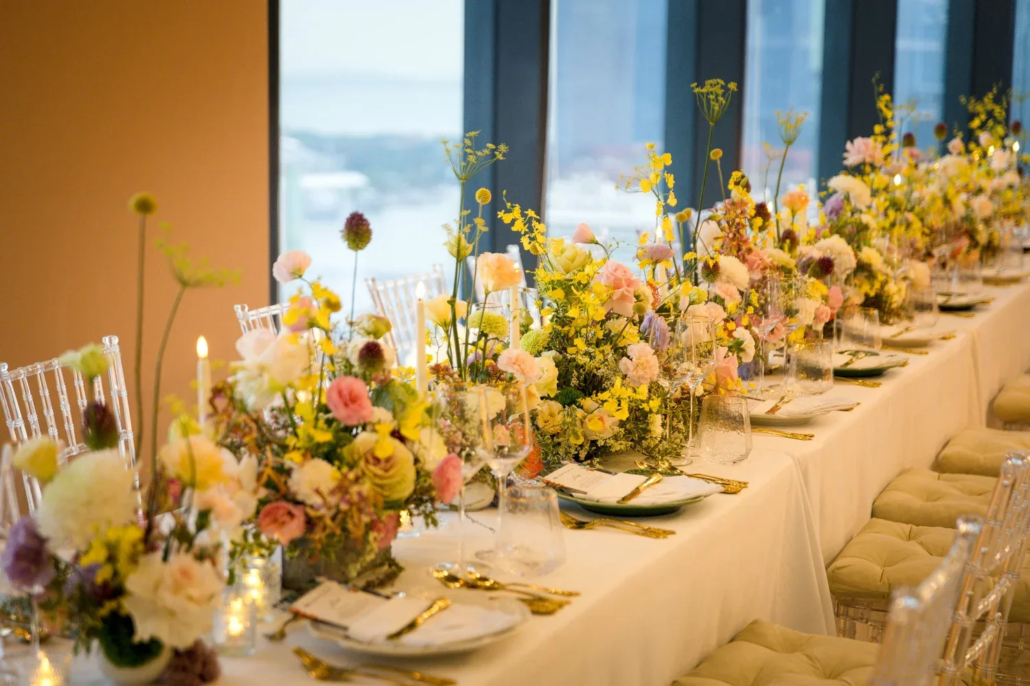 Warm golden long-table styling beside full-height windows